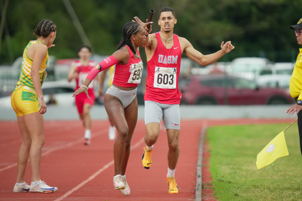 jorge maysonet en el momento de pase de batón a génesis castro para sellar con nueva marca en el relevo 4x400 mixto bajo el uniforme de la uagm.jpg (luis ortiz lai)